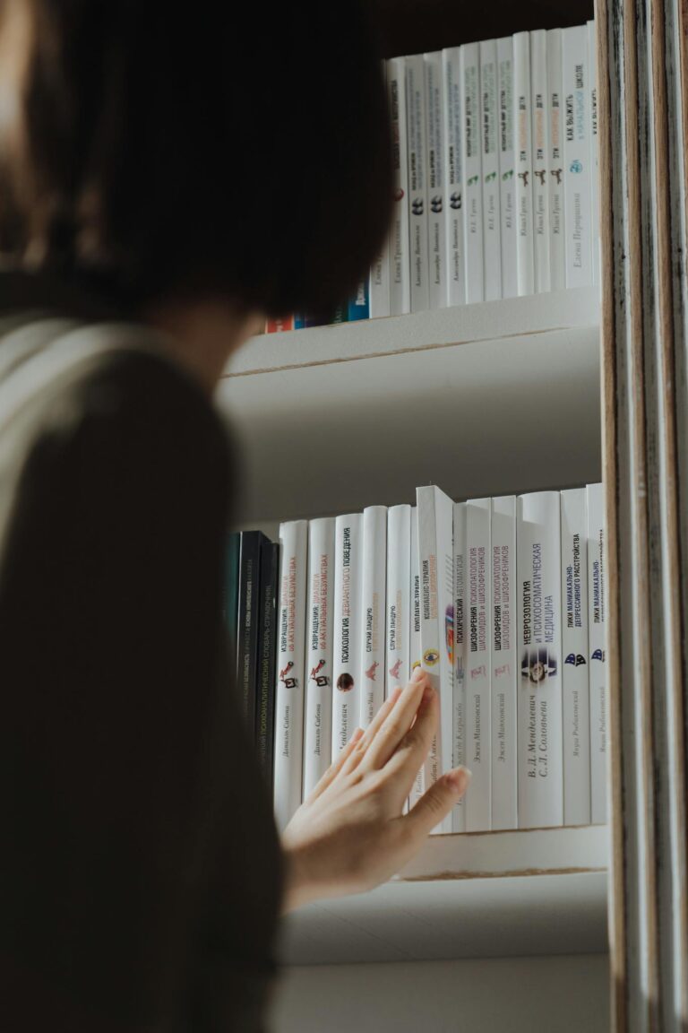 A person examines books on a shelf, capturing a moment of curiosity and learning.